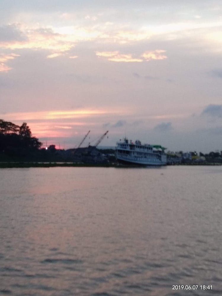 Sunset view of a river while a commercial boat passing through it