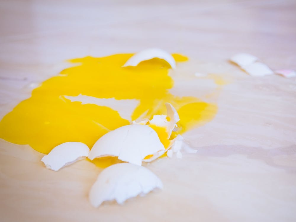 Broken Egg That Fell On The Floor Is Splattered With Yellow Yolk Everywhere