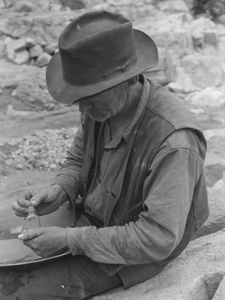 Gold Prospector Putting Flakes Of Gold Which He Has Recovered Through Wet Washing And Panning Into Bottle