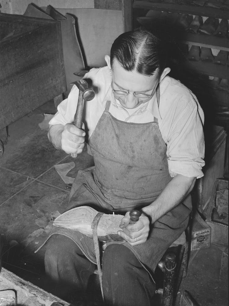 Bootmaker Pounding Wooden Peg Into Sole Of Boot In Building Up Sole With Several Pieces Of Leather