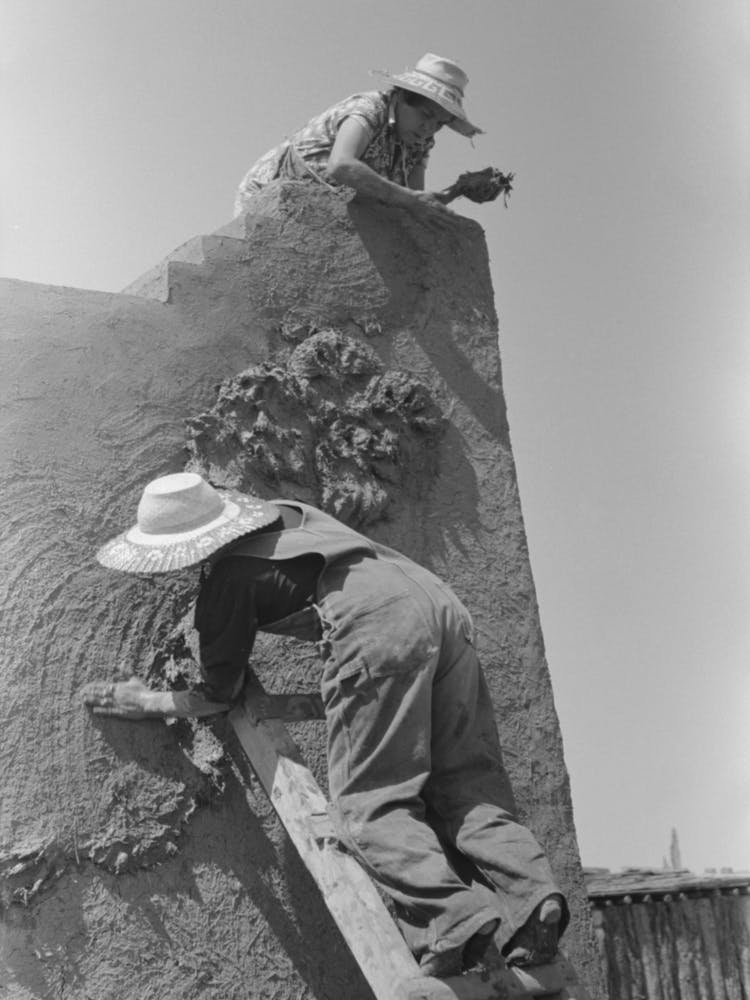 Spanisch-amerikanische Frauen verputzen ein Adobe-Haus, Chamisal, New Mexico Von Russell Lee