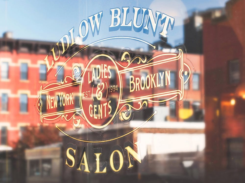 New York, USA I NYC skyline photography in window reflection from the barber shop to retro vintage gold graphic design typography with Brooklyn's red brick architecture for an abstract photographic composition
