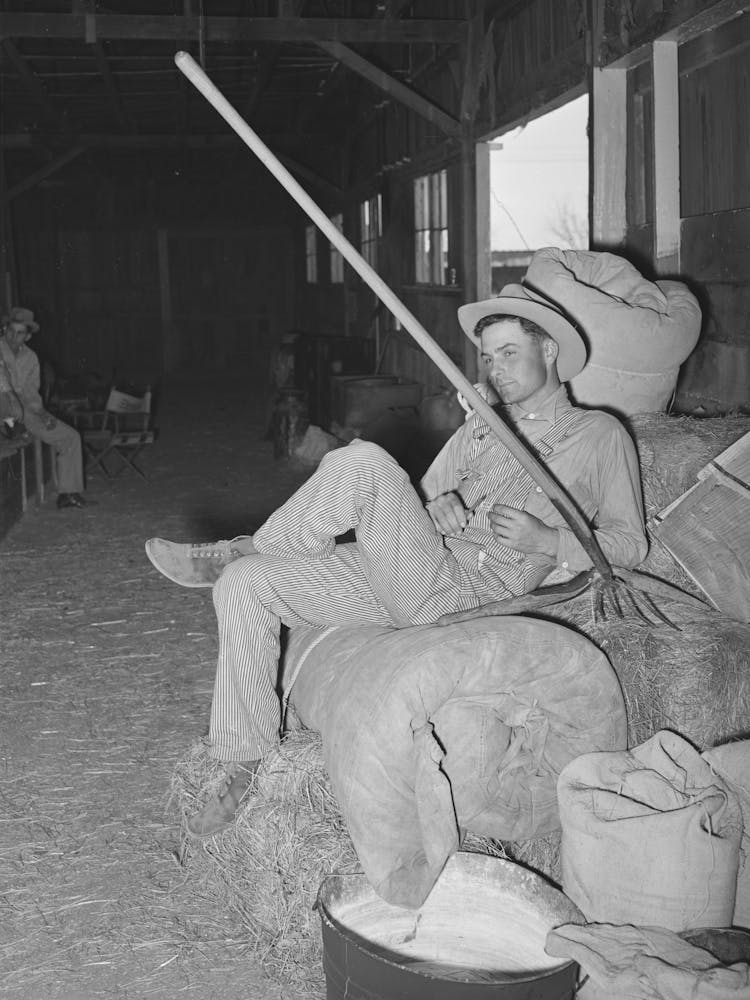 Cowboy Resting On Hay And Rolled Up Camp Bed At The Barn At San Angelo Fat Stock Show, San Angelo, Texas By