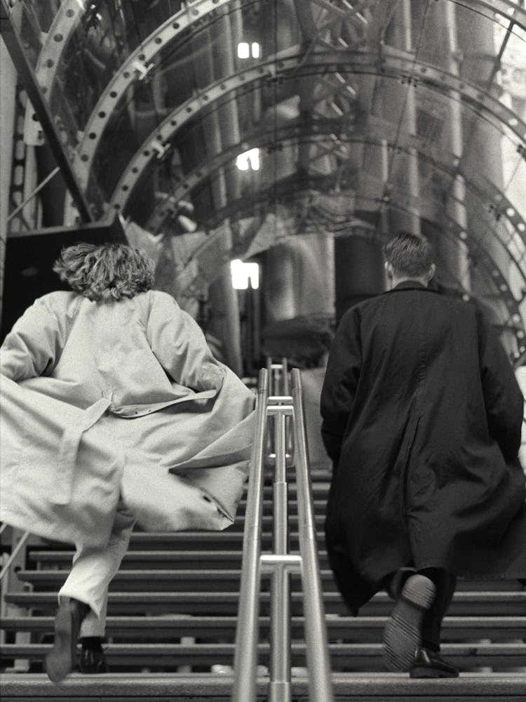 Couple Running Up Steps In Big Coats Black And White