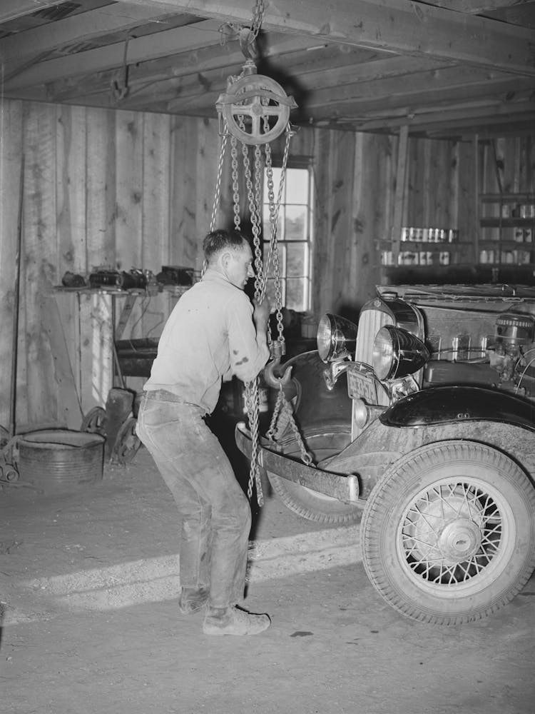 Garage Owner Hoisting Car So That He Can Make Repairs, Pie Town, New Mexico By Russell Lee