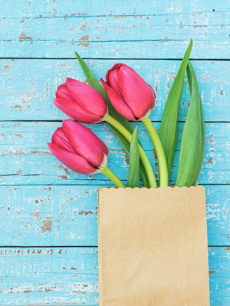 Tulips In A Paper Bag On A Wooden Background