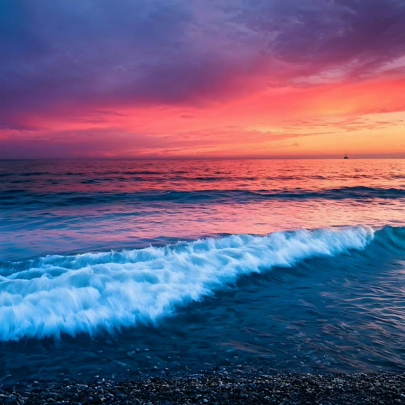 A fiery pink sky bleeds color into a calm, azure sea