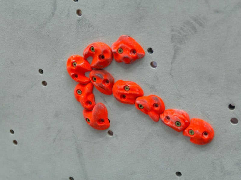 Red Climbing Holds In The Shape Of An Arrow On Grey Wall