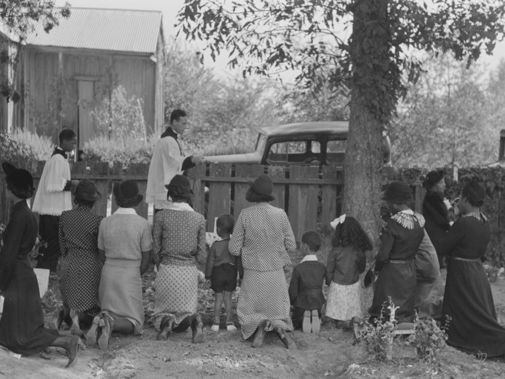 Family Kneeling At Graves Of Relatives, And Being Blessed By Priest With Holy Water, New Roads, Louisiana By Russe