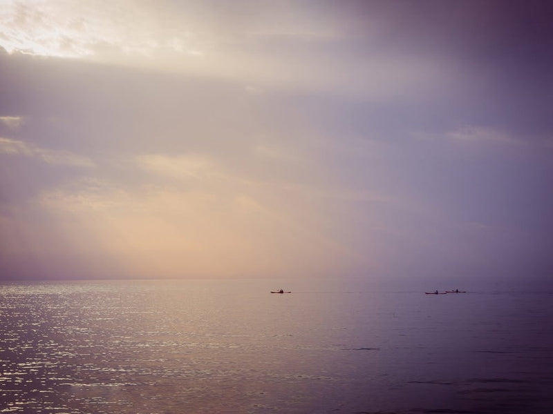 Three Canoes Sailing At Sea During Sunset