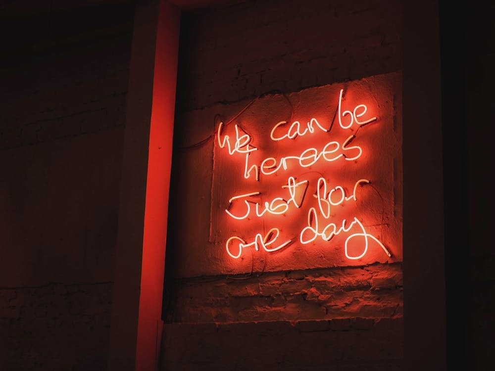 London, England I Vibrant red neon mantra captured in a restaurant window photography with a warm urban ambience with an inspiring phrase about we can be heroes just for one day with a luminous decor light
