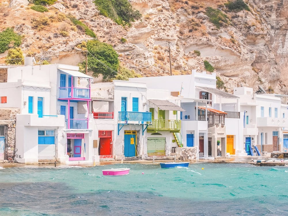 Milos, Griechenland | Buntes Fischerdorf vom Hafen von Klima bis zum paradiesischen türkisfarbenen Wasser der Kykladen mit einer Retro-Vintage-Sommer-Pastell-Ästhetik und minimalistischer geometrischer weißer Architekturfotografie auf dem Berg