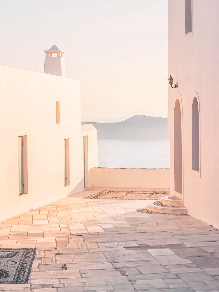 Milos, Greece I Sunset light in Oia Cyclades white architecture with its summer pastel aesthetic with panoramic view photography of the Mediterranean sea ocean and the orange golden light of the greek mountain