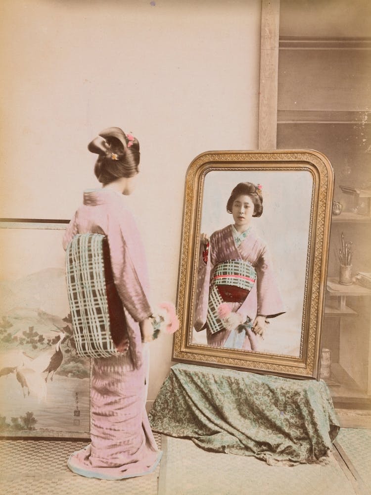 Junge japanische Frau blickt in den Spiegel