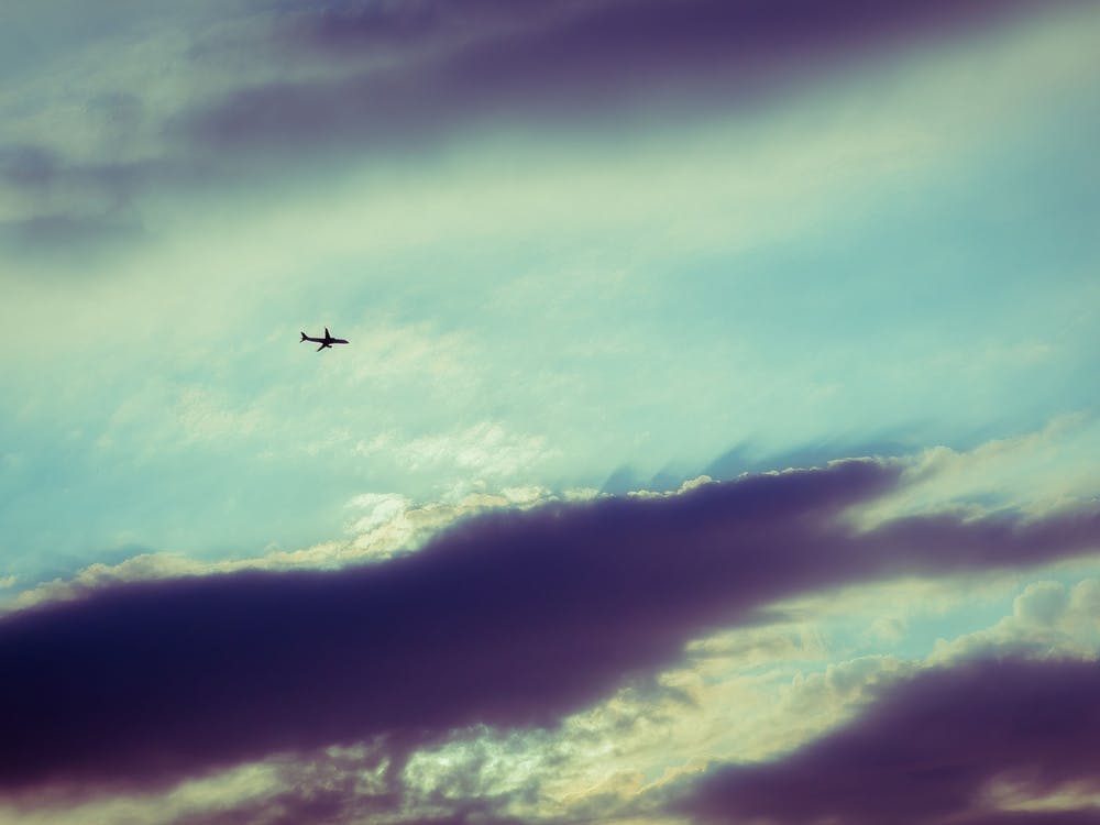 Silhouette Of An Airplane Flying In Sunset Sky