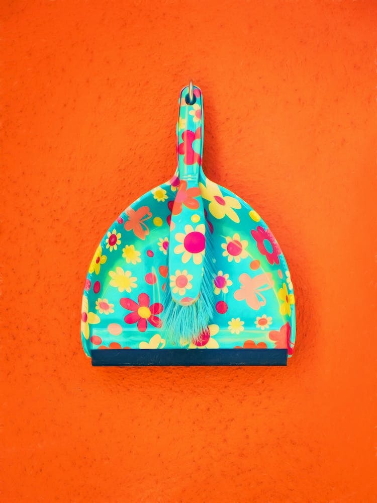 Floral Dustpan & Brush Against Orange Painted Wall