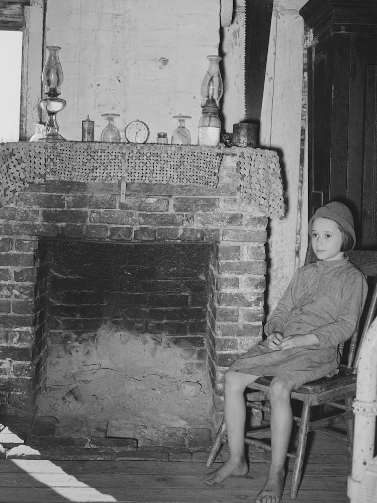 Daughter Of Cajun Day Laborers Sitting In Front Of Fireplace In Home Near New Iberia, Louisiana By Russell Lee