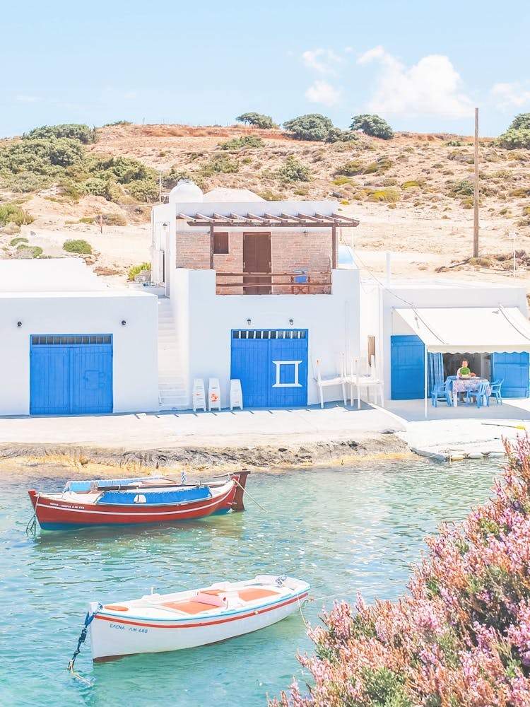 Milos, Greece I Cyclades blue and white fishing village architecture with Bougainvillea pink flowers wild boho nature photography and colorful boats in paradise blue turquoise waters of the Mediterranean sea