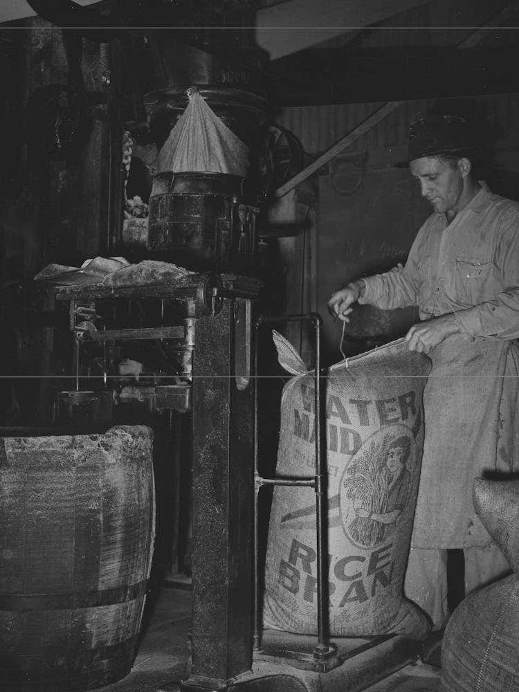 Sewing Bag Of Rice Brand After Being Weighed In Rice Packaging Process,Crowley, Louisiana By Russell Lee