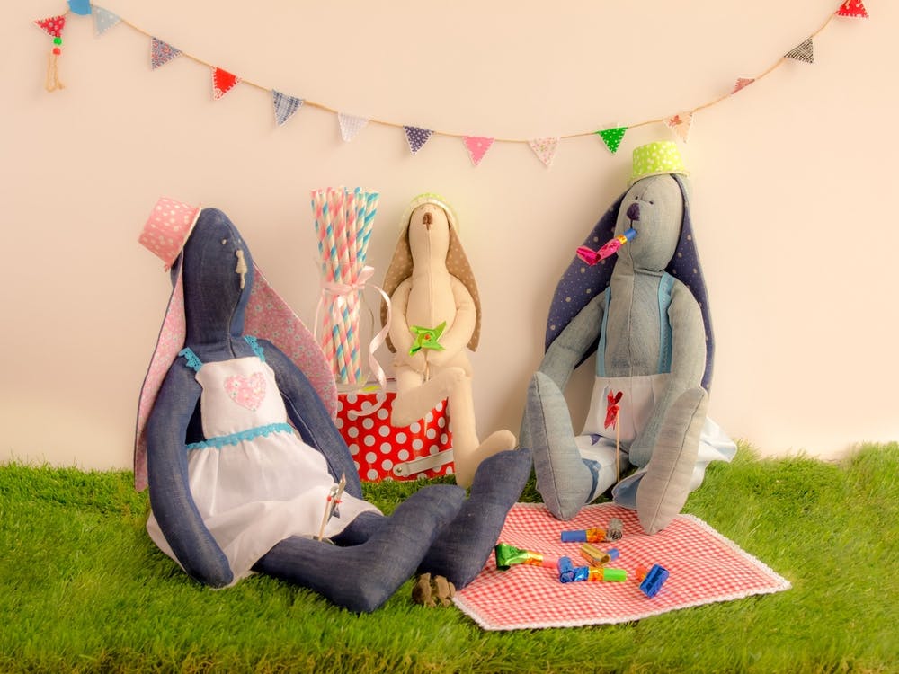 Handmade Cloth Rabbit Dolls Sitting On The Grass And Celebrating In Party Concept