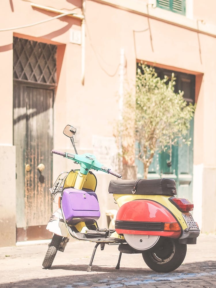 Rome, Italie I Scooter italien vintage pastel multicolore dans une charmante rue authentique du Trastevere avec lumière d'été et ambiance méditerranéenne de la dolce vita pour une photographie de scène italienne authentique