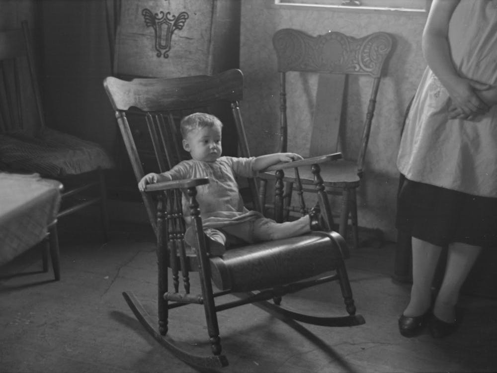 One of L,H, Nissen's children in rocking chair,Nissen shack near Dickens, Iowa