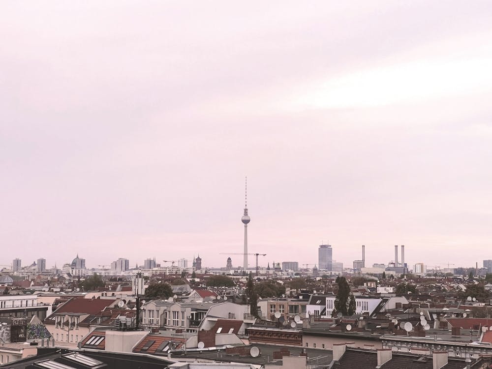 Berlin, Germany I Urban skyline with Fernsehturm tower at sunset under a pastel pink sky in minimal poetic composition photography blending geometric lines soft light and raw industrial architecture
