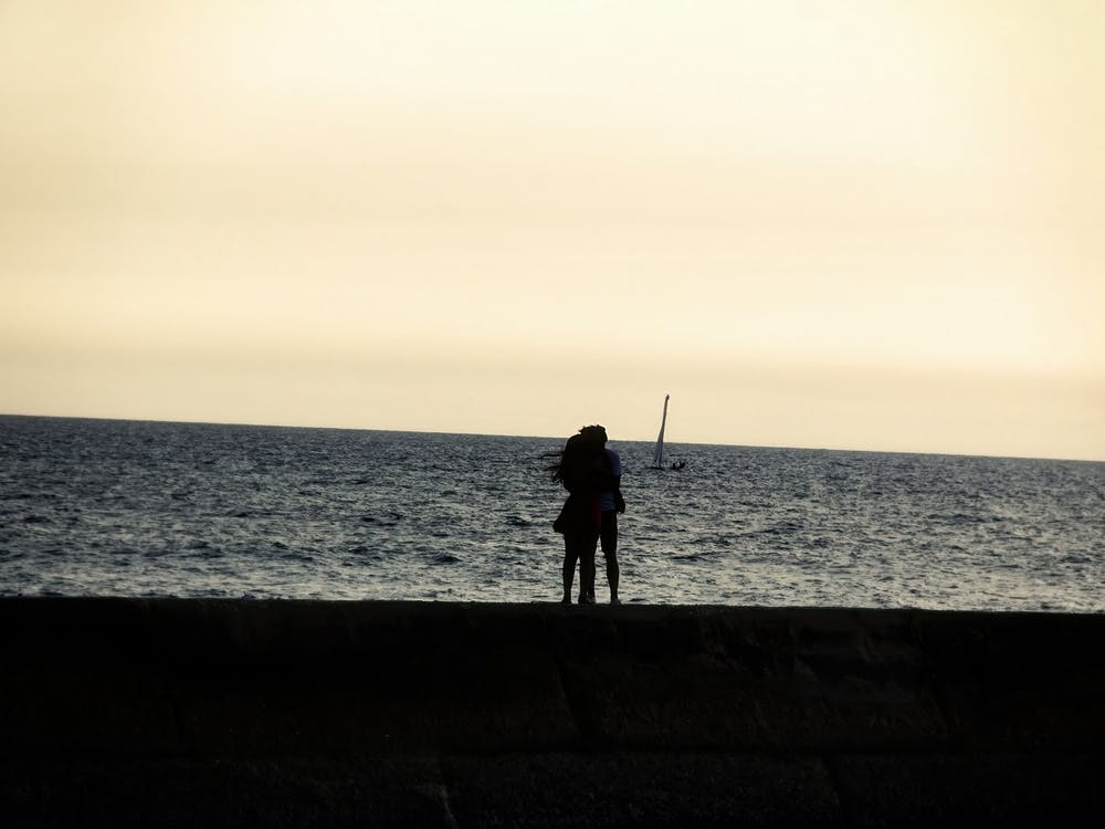 Silhouette Of An Embracing Couple Looking At The Sea