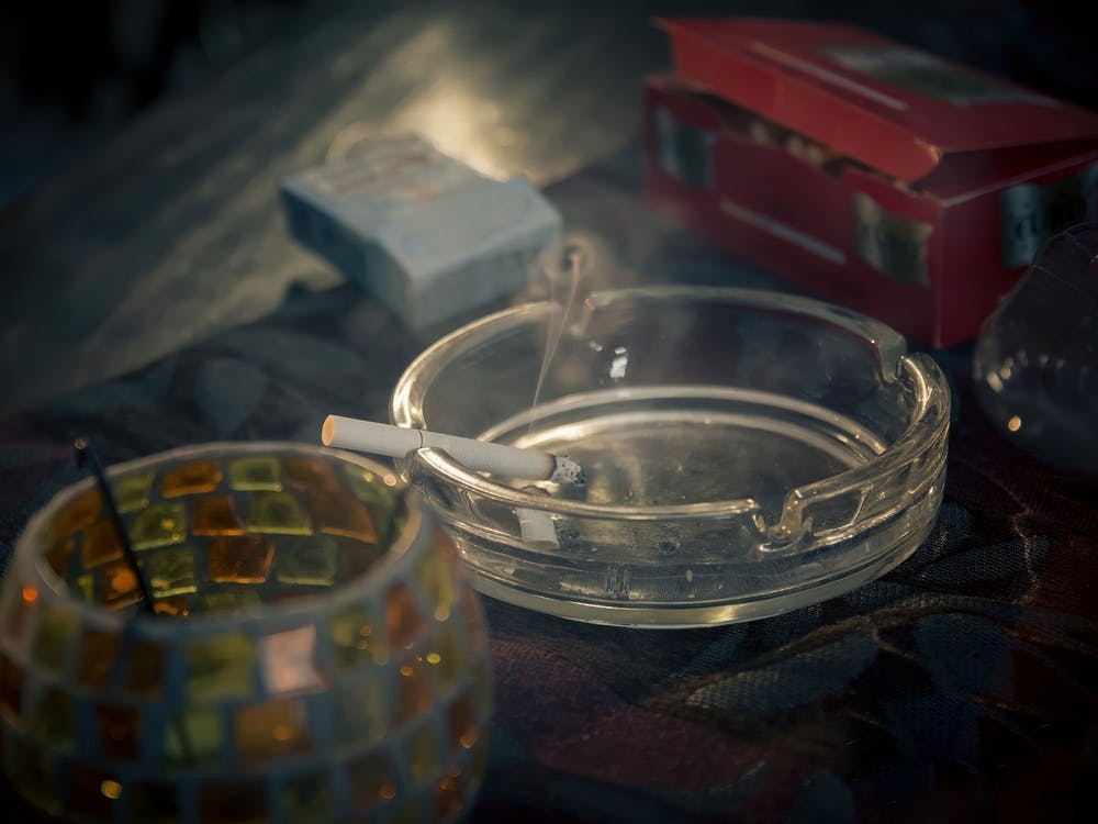 Lit Cigarette In A Glass Ashtray