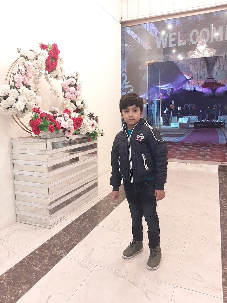 Boy Standing In Front Of Flowers