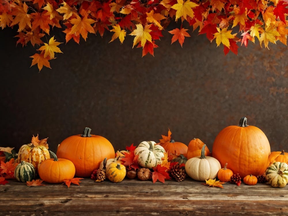 Autumn Themed Table Decoration Scattered Maple Leaves In Warm Shades Intermixed With Small Pumpkin (1)