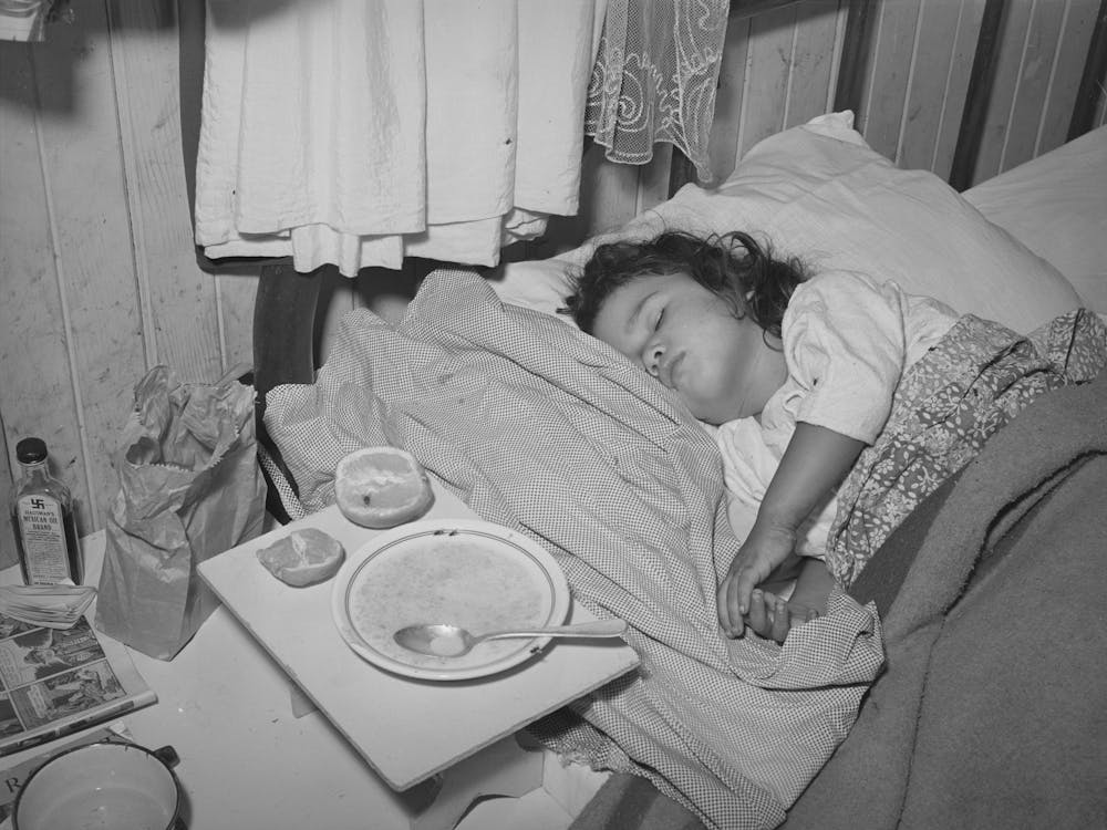 Sick Child In Bedroom Of House In The Mexican Section, Seven Children And Two Adults Sleep In Two Small Rooms A