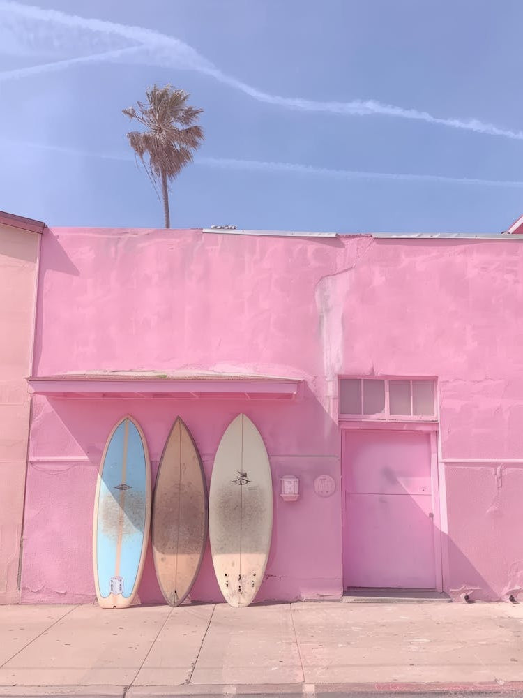 Surfboards In Front Of A Pink Building