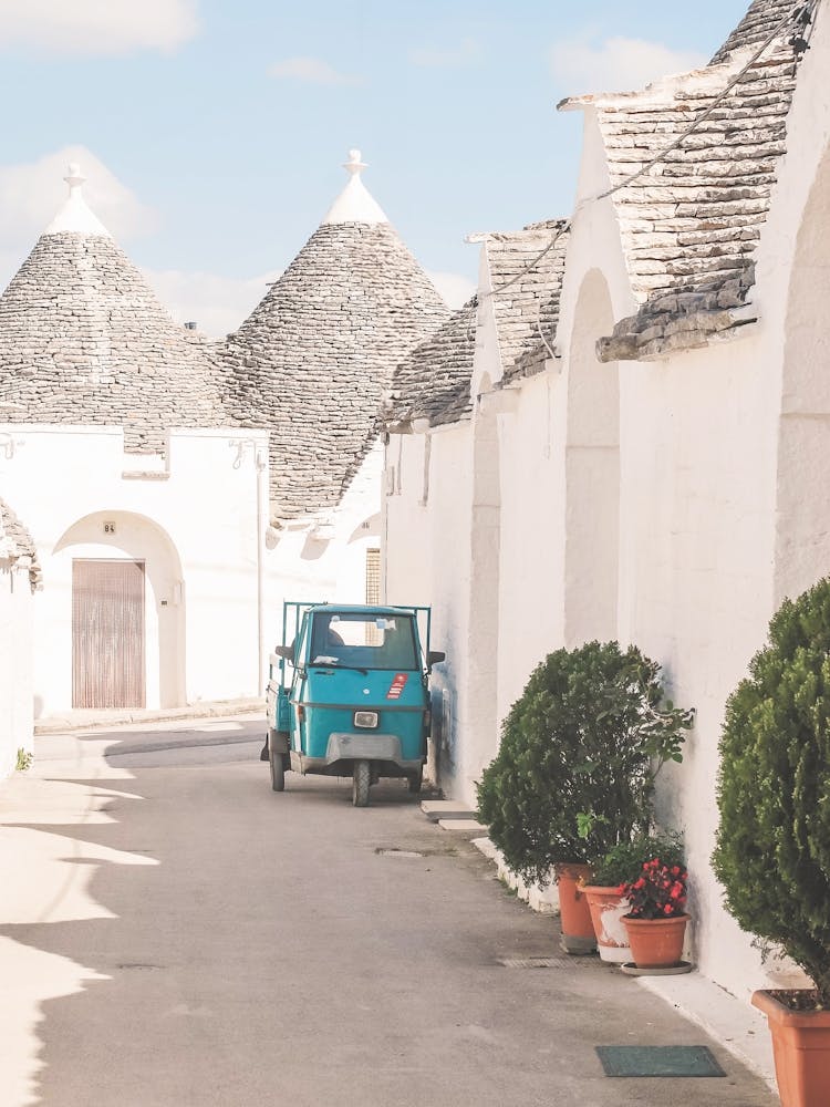 Puglia, Italy I Quiet street in Alberobello white village with trulli architecture and Vespa scooter in a retro vintage summer pastel aesthetic photography for living la dolce vita in the Mediterranean place