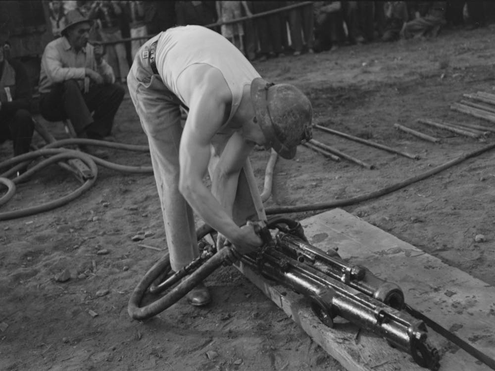 Miner Attaching Airhose To Power Drill Which He Will Use In Drilling Contest, Labor Day Celebration, Silverton