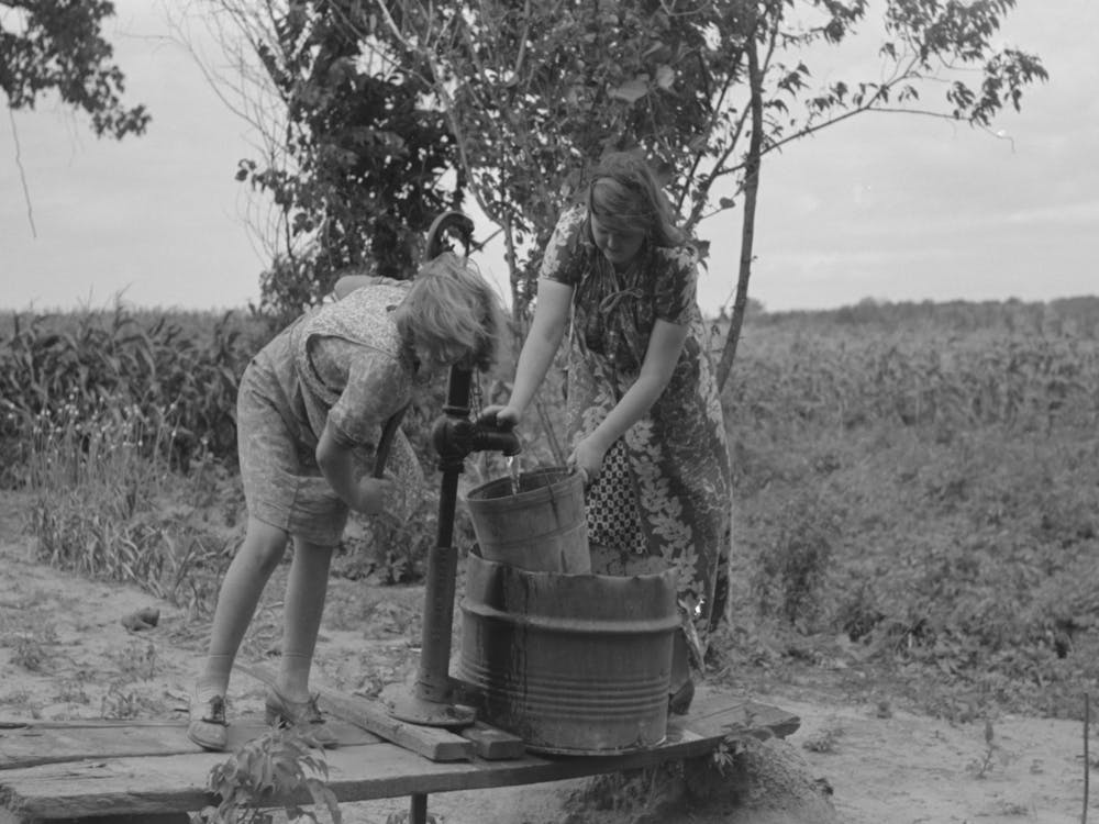 Pumping Water Near Muskogee, Oklahoma, Daughters Of Farmer About To Migrate To California By Russell Lee