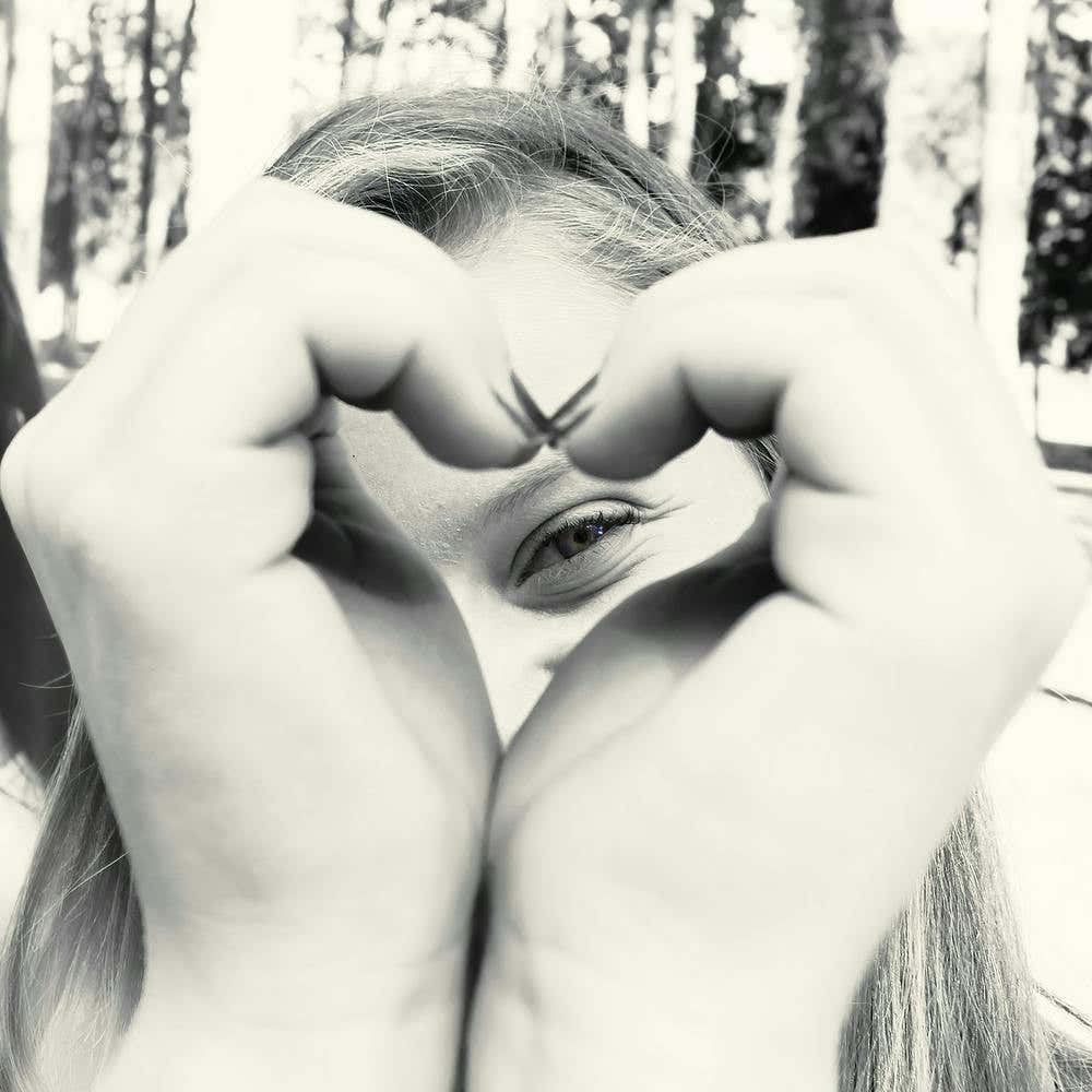 Woman Peeking Through A Heart Shape She Does With Her Hands 1