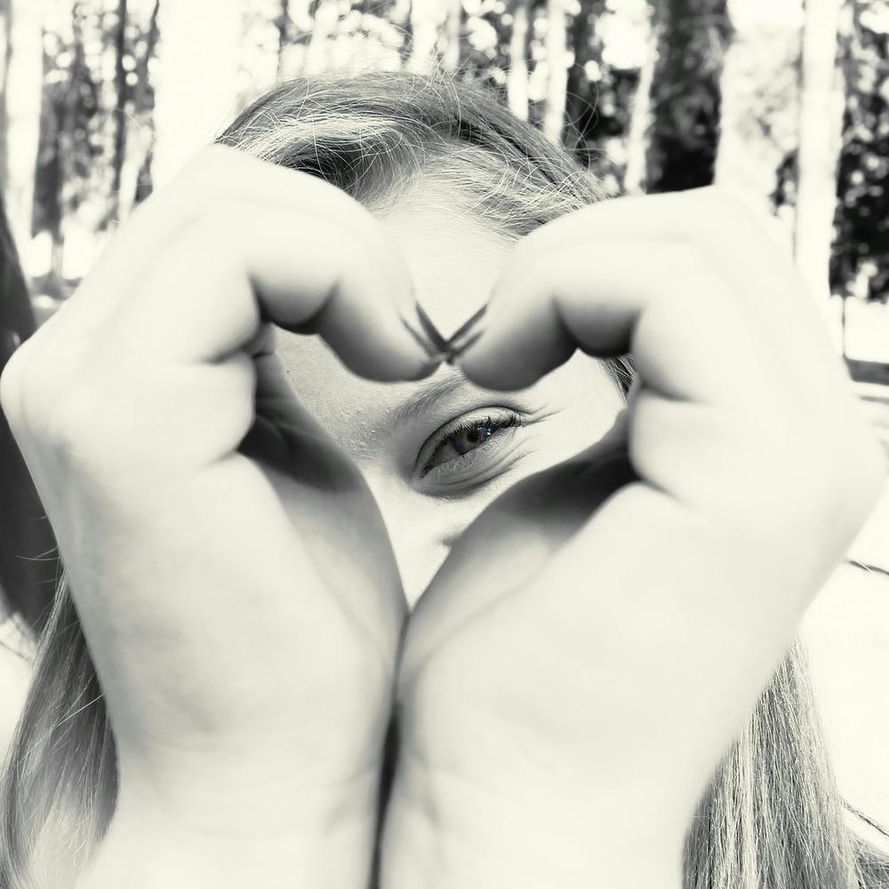 Woman Peeking Through A Heart Shape She Does With Her Hands 1