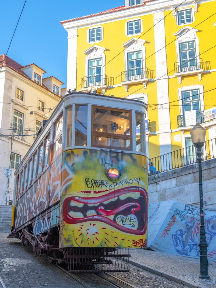 Bright yellow cable car with graffiti in Lisbon, Portugal - summer street and travel photography by Christa Stroo Photography