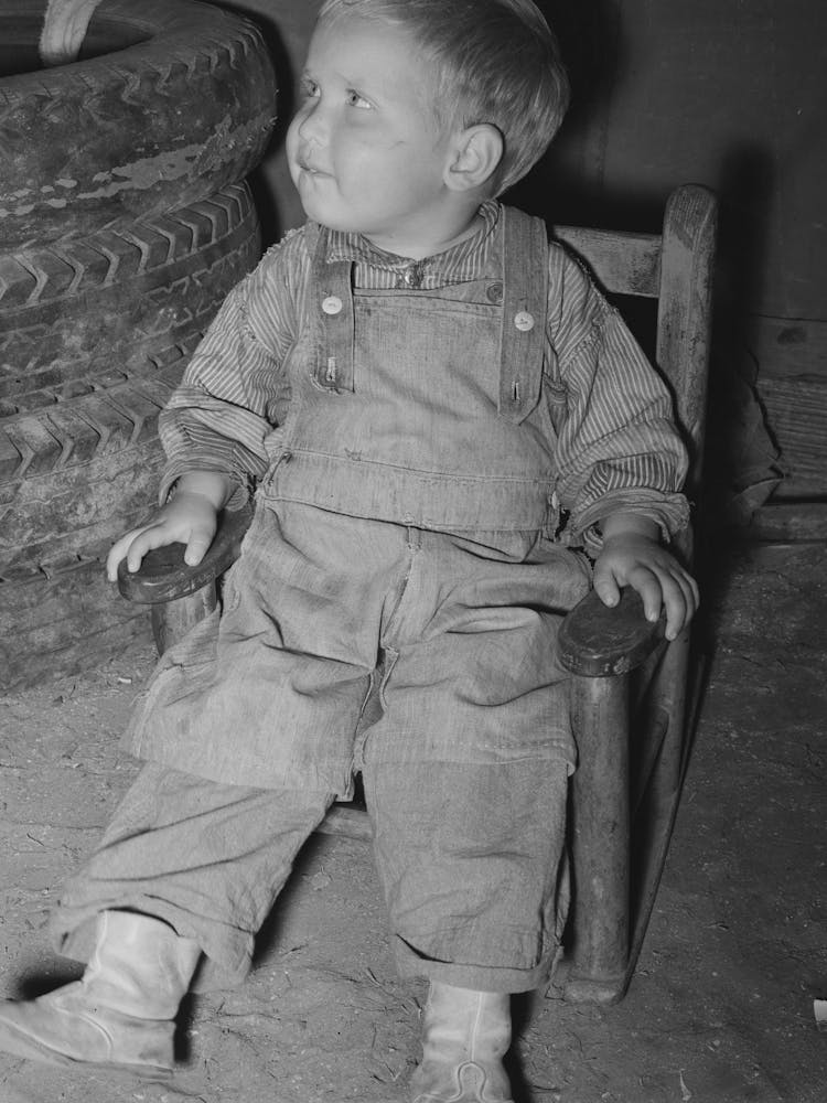 Untitled Photo, Possibly Related To Child Of Migrant Auto Wrecker Sitting Next To Tires In Corner Of Tent Home