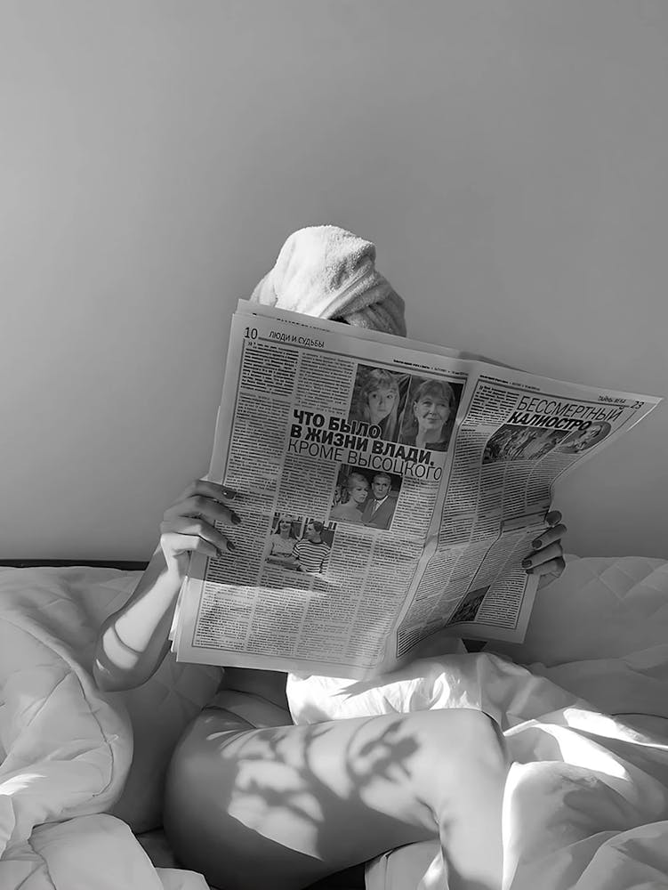 Frau liest Zeitung im Bett
