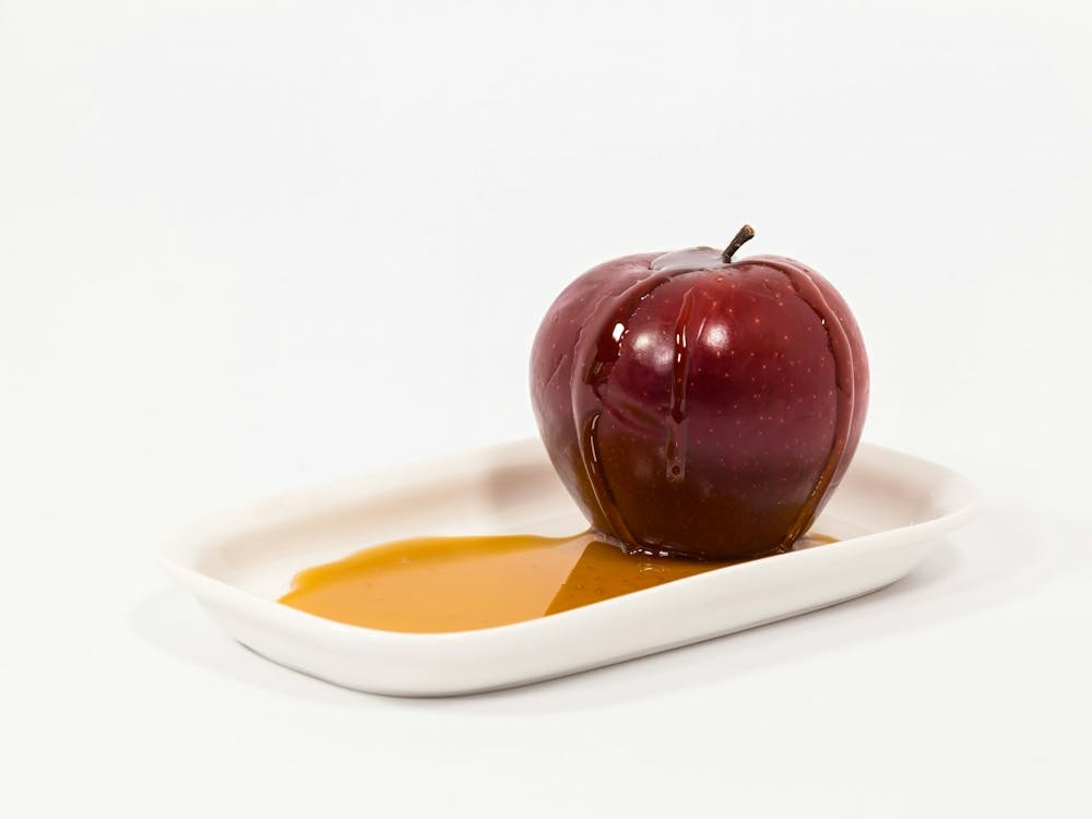 Red Apple With Drops Of Honey On White Plate With Honey Isolated On A White Background