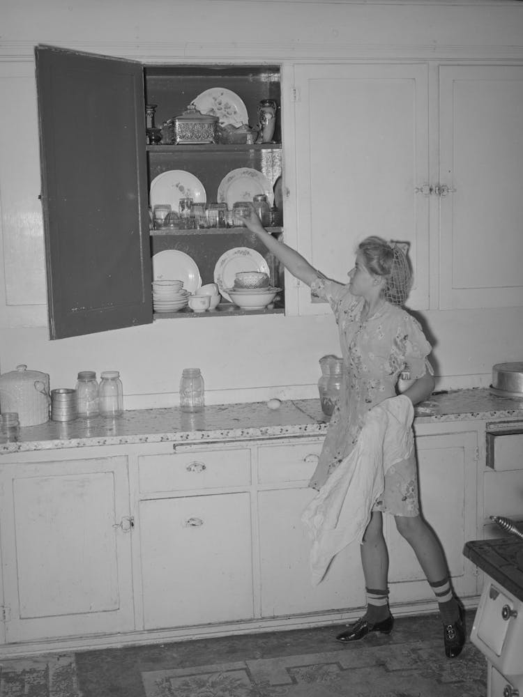 Tochter eines Mormonenbauern, die Geschirr in einem Küchenschrank in Box Elder County, Utah wegräumt