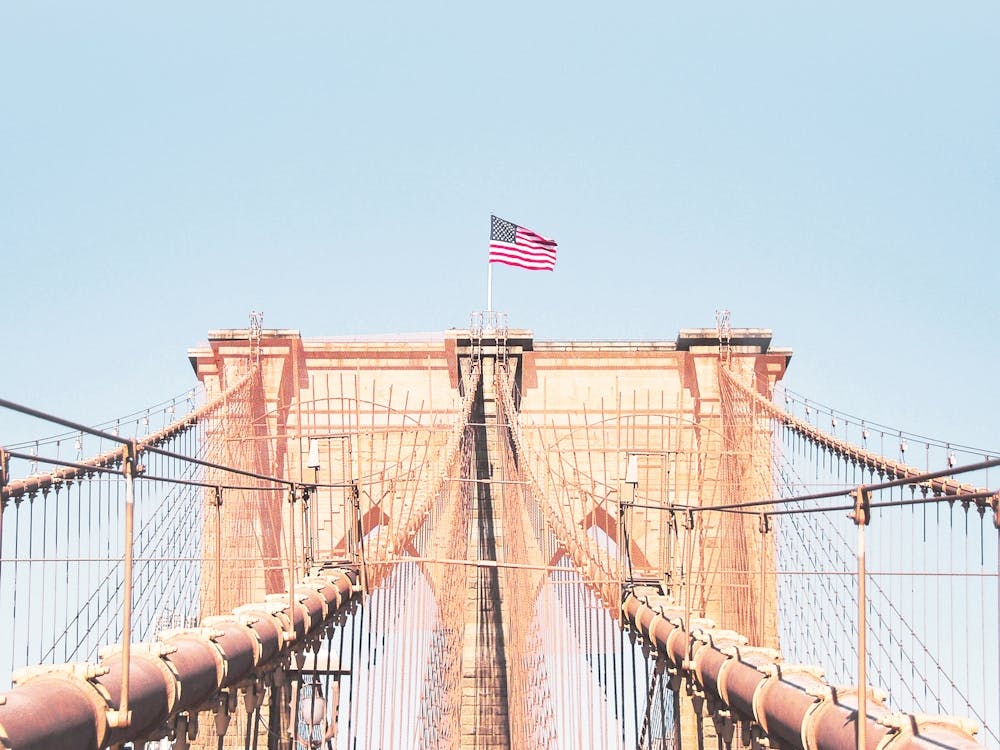 New York, USA I Brooklyn Bridge in the middle view with the film retro vintage aesthetic atmosphere on American flag for a minimalist, geometric symmetrical photography in blue pastel summer colors