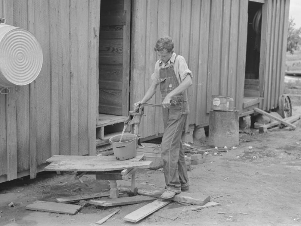 Son Of Sharecropper Pumping Water In Rear Of Cabin Home, New Madrid County, Missouri By Russell Lee