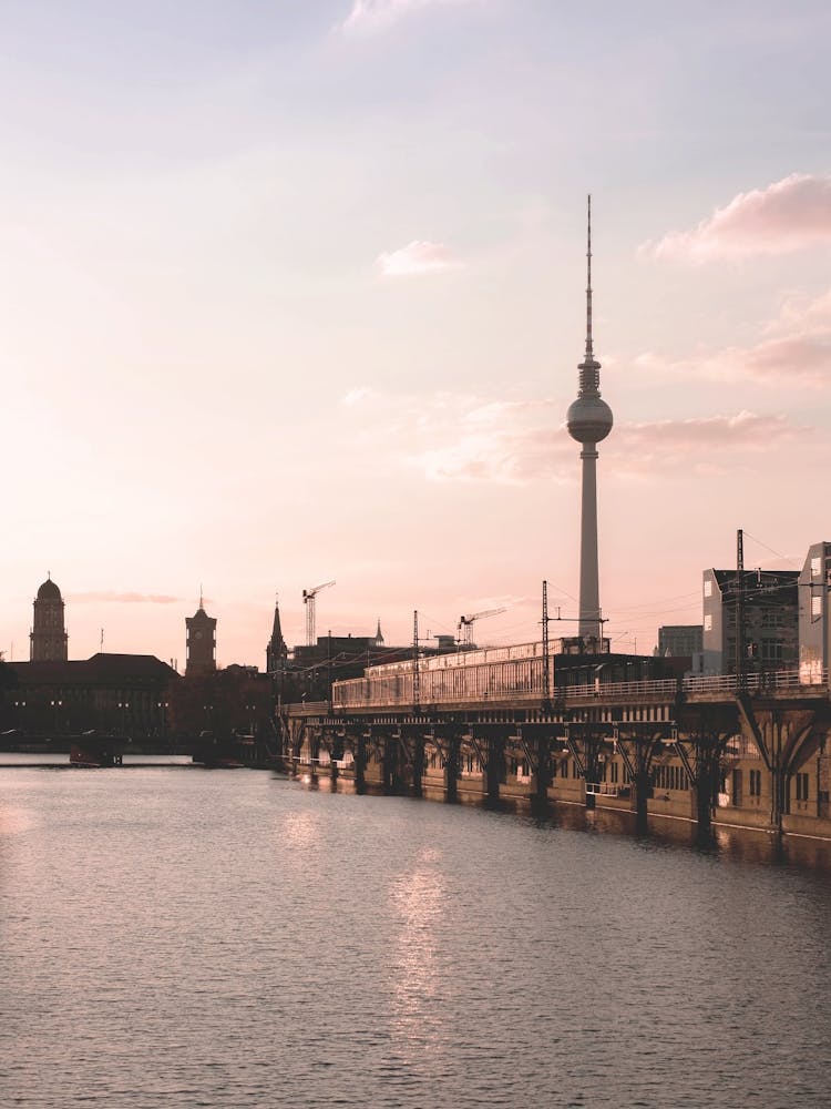 Berlin, Germany I Poetische Silhouette der Berliner Skyline mit Fernsehturm bei Sonnenuntergang in pastellrosa und blauen Tönen Fotografie, gespiegelt in der Spree für eine romantische und minimalistische urbane Stimmung