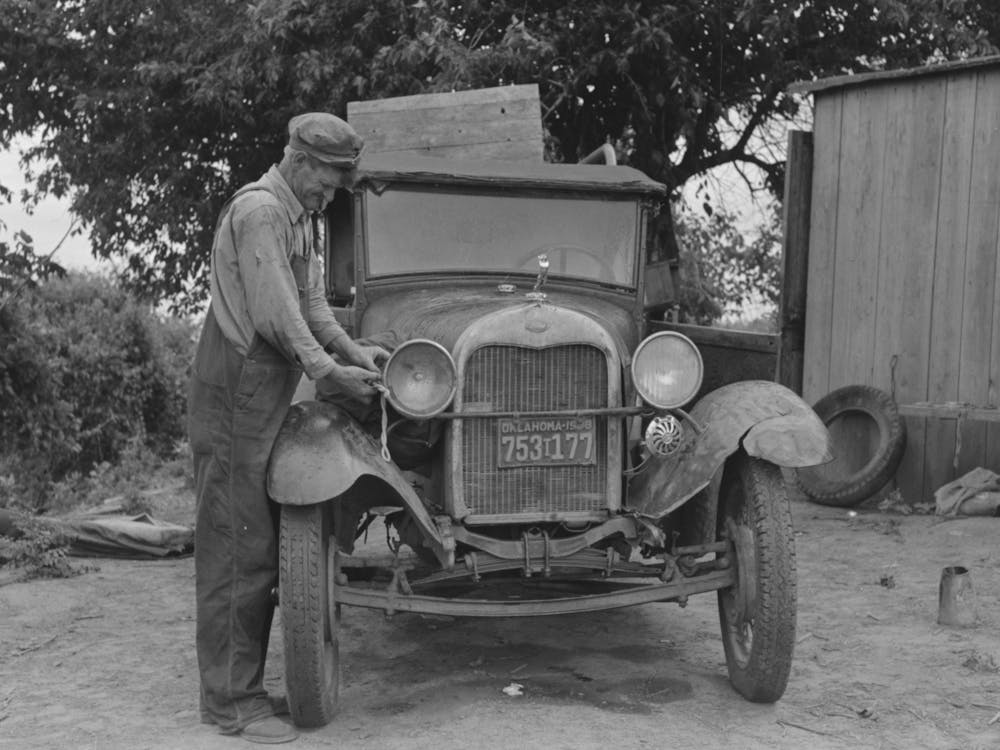 Untitled Photo, Possibly Related To Elmer Thomas, Migrant To California, Tying Sack Of Laundry Onto Front Lamp