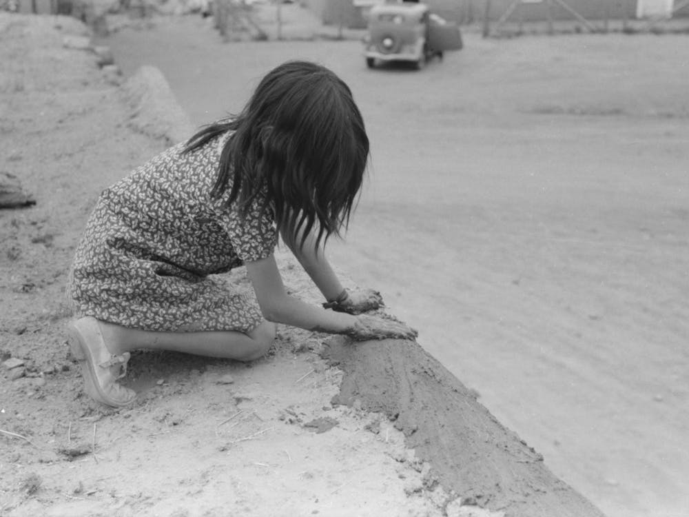 Spanish American Girl Plastering Edge Of Roof Of Adobe House