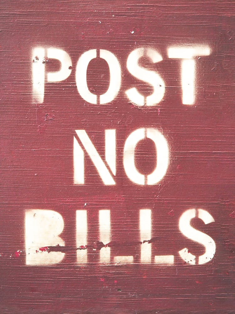 New York, USA I Post no bills street art in text with white spray painted typography on a dark red wooden background to notify of a posting ban with a contrast minimalist letter graphic design photography
