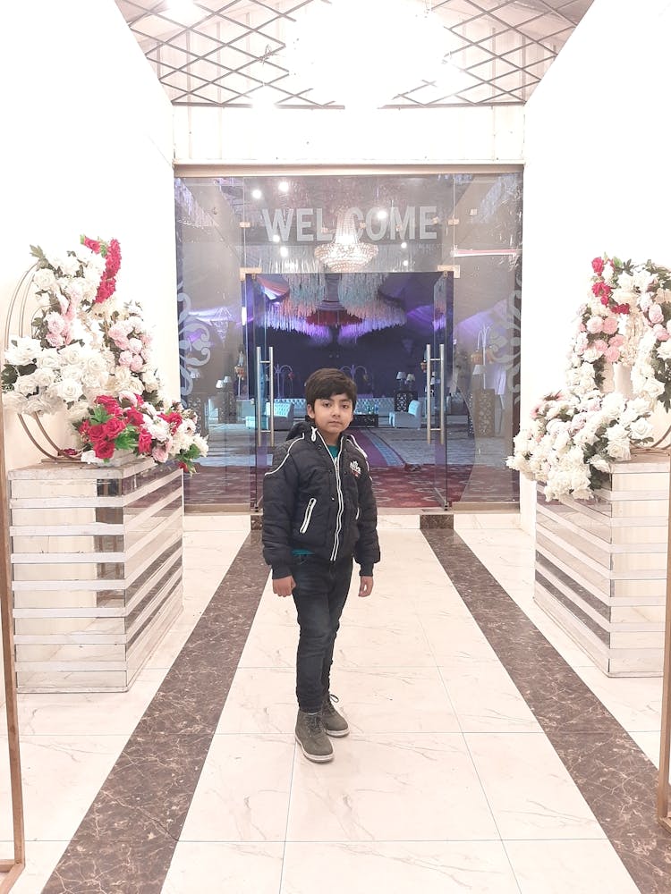 Boy Standing In Front Of Flowers 1